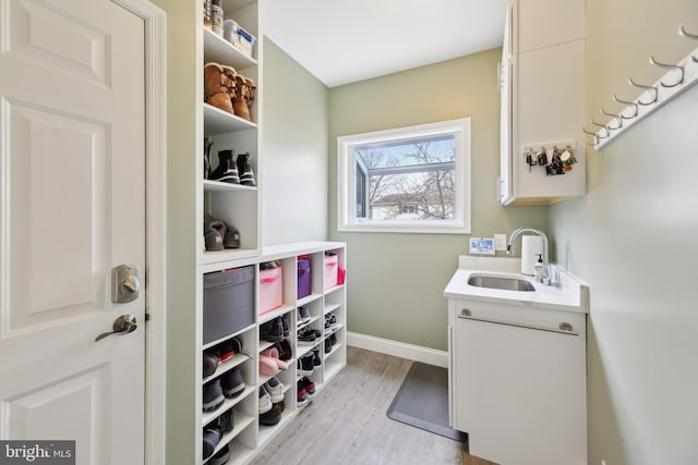 washroom with light wood-style floors, baseboards, and a sink