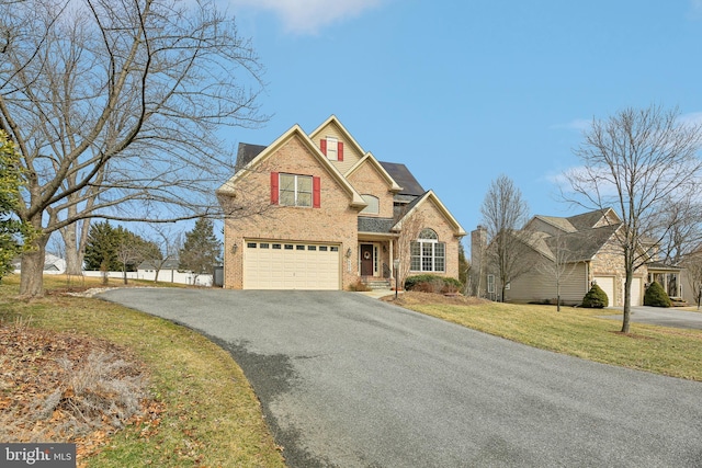 traditional-style home featuring brick siding, driveway, and an attached garage