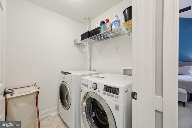 laundry room featuring laundry area, baseboards, washing machine and clothes dryer, and light tile patterned floors