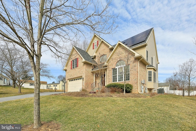 traditional-style home featuring aphalt driveway, a front yard, brick siding, and solar panels