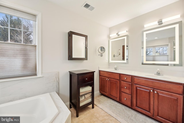 full bath featuring visible vents, a sink, a garden tub, and double vanity