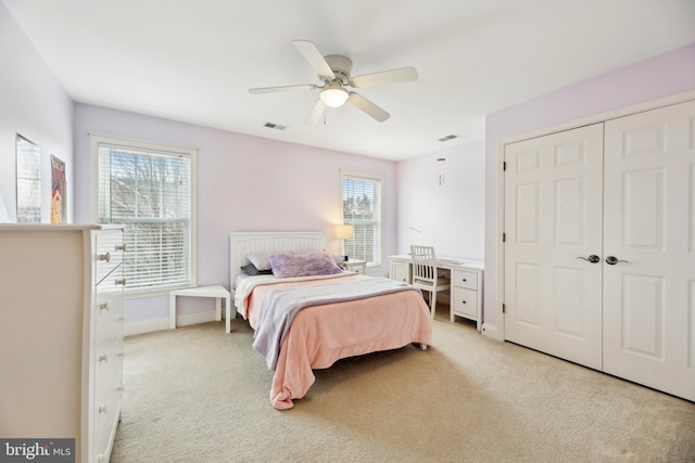 bedroom with ceiling fan, light colored carpet, visible vents, baseboards, and a closet