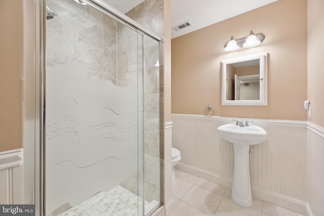 bathroom with visible vents, toilet, a wainscoted wall, tile patterned floors, and a shower stall