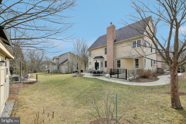 back of property with a chimney, a lawn, and a patio