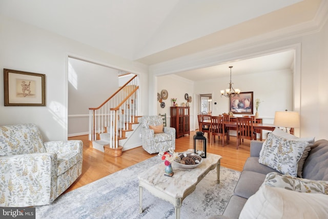 living room featuring a chandelier, lofted ceiling, light wood-style floors, stairway, and crown molding