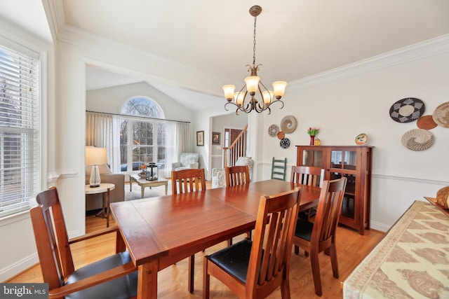 dining area with a chandelier, lofted ceiling, stairs, light wood-type flooring, and crown molding