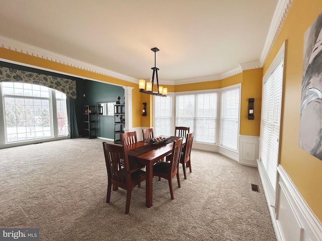 carpeted dining room featuring a notable chandelier and ornamental molding