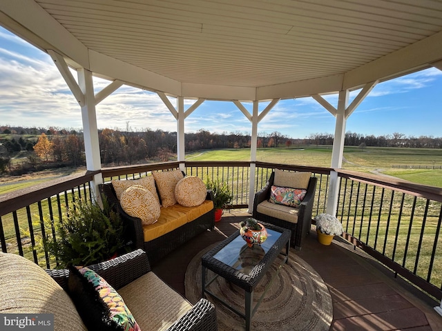 wooden terrace with a rural view, a lawn, and outdoor lounge area