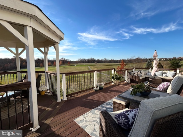 wooden terrace featuring a rural view, a lawn, and outdoor lounge area