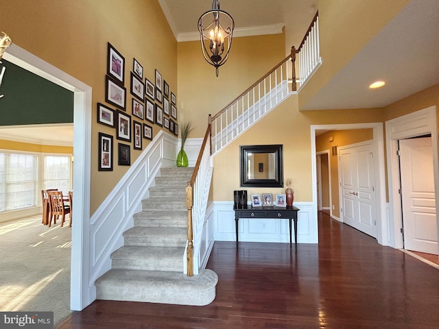 stairs with a notable chandelier, crown molding, and wood-type flooring