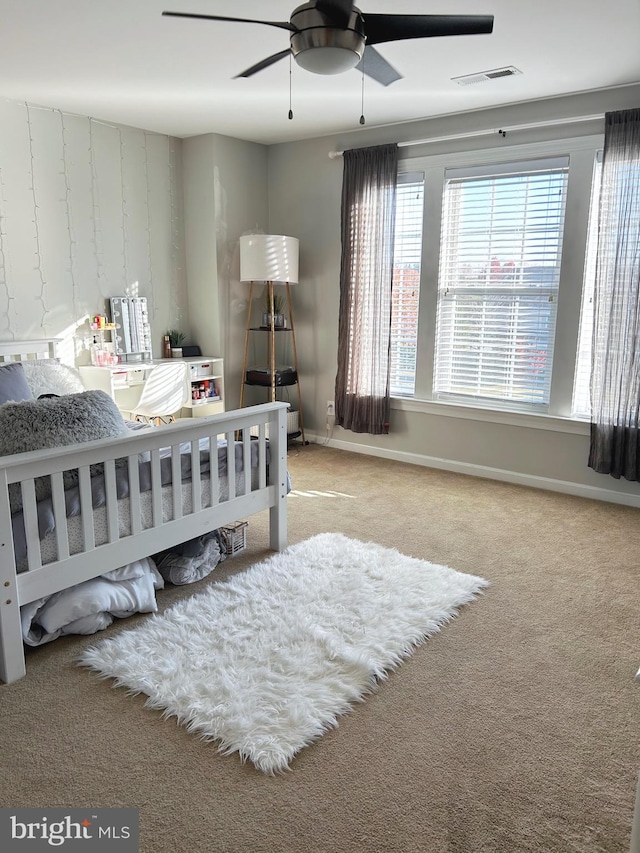 carpeted bedroom featuring multiple windows and ceiling fan