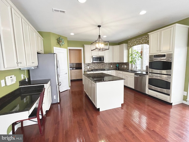 kitchen with decorative light fixtures, stainless steel appliances, white cabinetry, and a center island