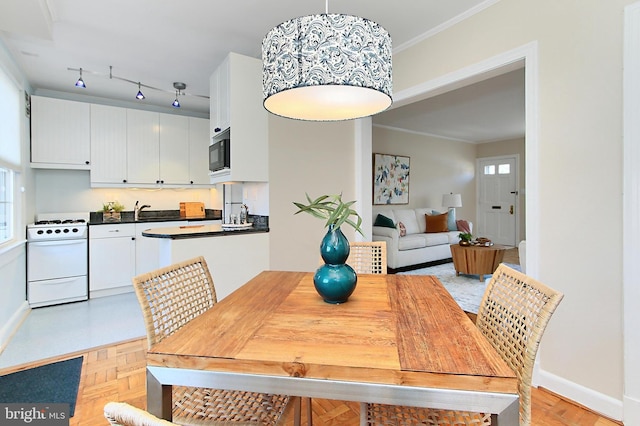 dining room featuring light parquet flooring, ornamental molding, and sink