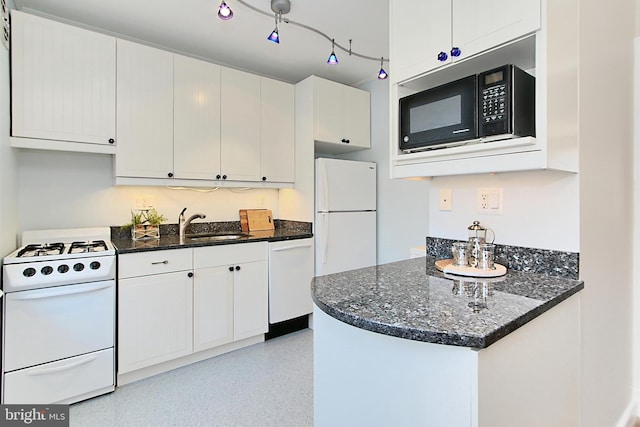 kitchen with sink, white appliances, dark stone countertops, track lighting, and white cabinets