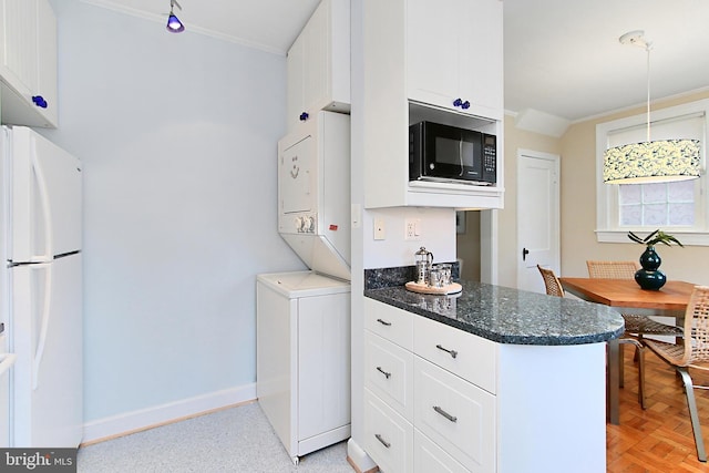 kitchen with pendant lighting, stacked washer and clothes dryer, white cabinets, and white fridge