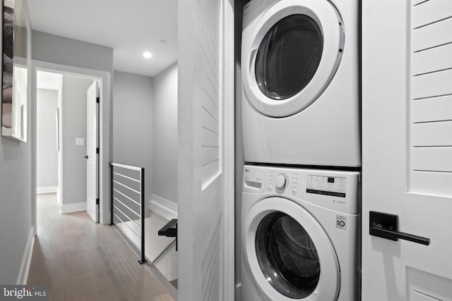 laundry area featuring stacked washer / dryer and light hardwood / wood-style floors