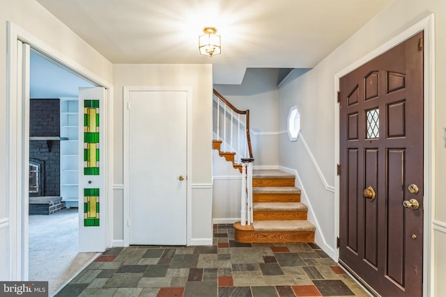 entryway with a fireplace and dark carpet