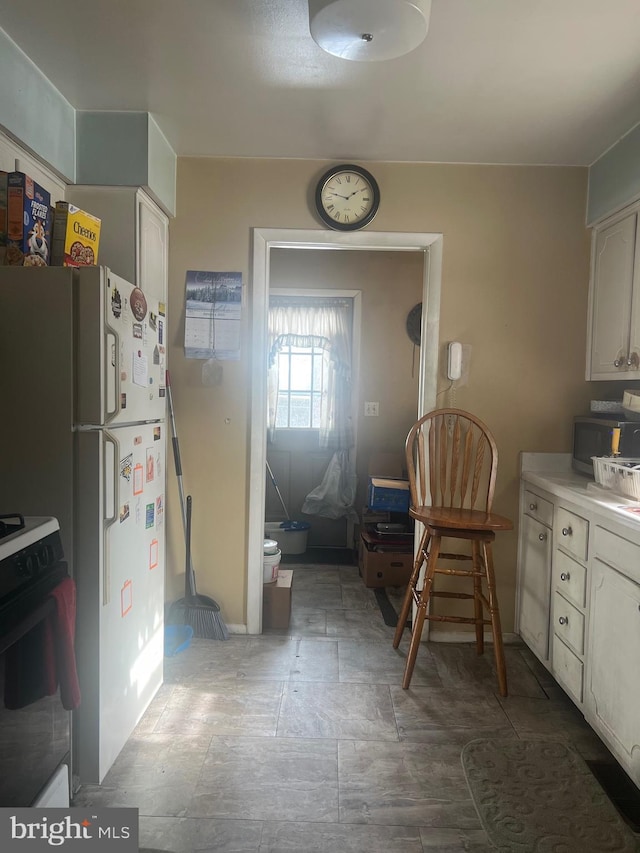 kitchen featuring white cabinets, white fridge, and stove