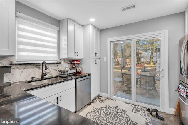 kitchen with sink, backsplash, white cabinetry, and dishwasher