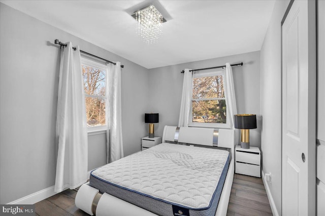 bedroom featuring an inviting chandelier and dark wood-type flooring