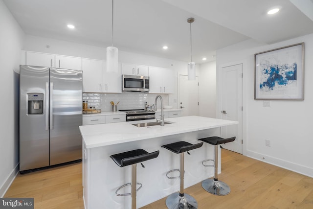 kitchen with decorative light fixtures, sink, appliances with stainless steel finishes, and white cabinetry