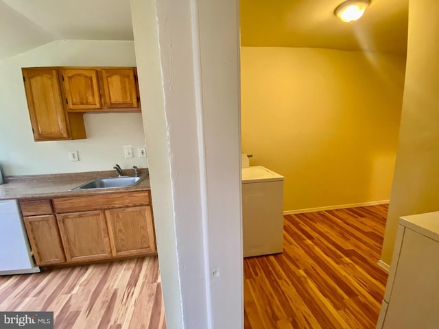 kitchen featuring washer / dryer, light wood-type flooring, dishwasher, and sink