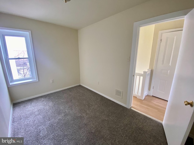 spare room with dark carpet