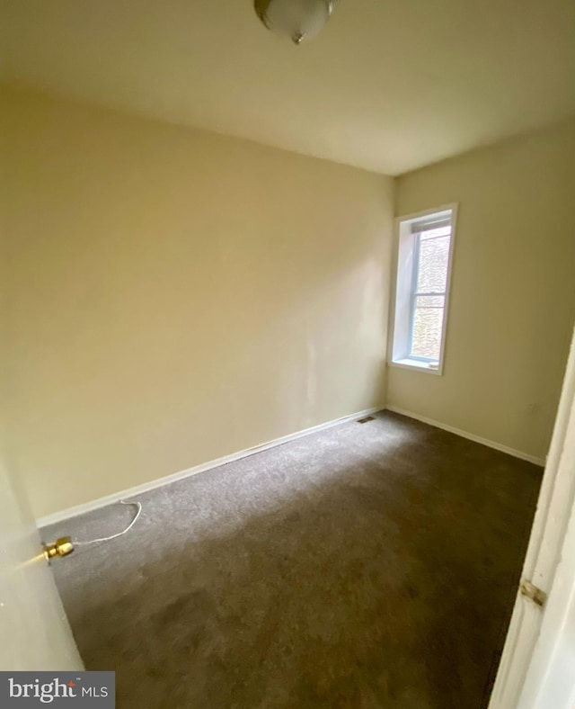 spare room featuring dark carpet