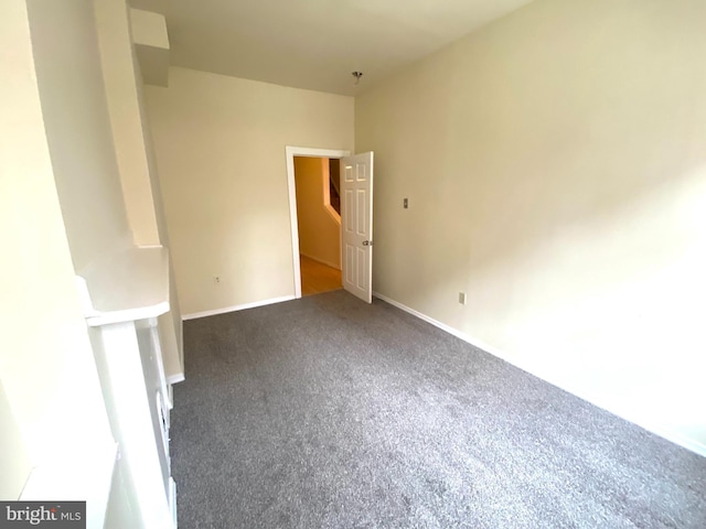 unfurnished room with dark colored carpet