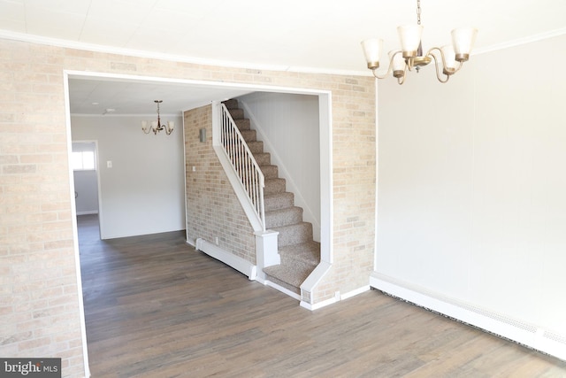 stairway with a baseboard heating unit, a notable chandelier, crown molding, and hardwood / wood-style floors