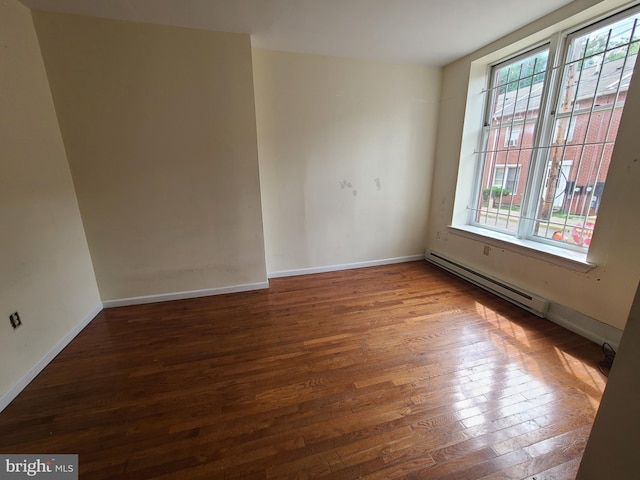 spare room with baseboard heating and hardwood / wood-style floors