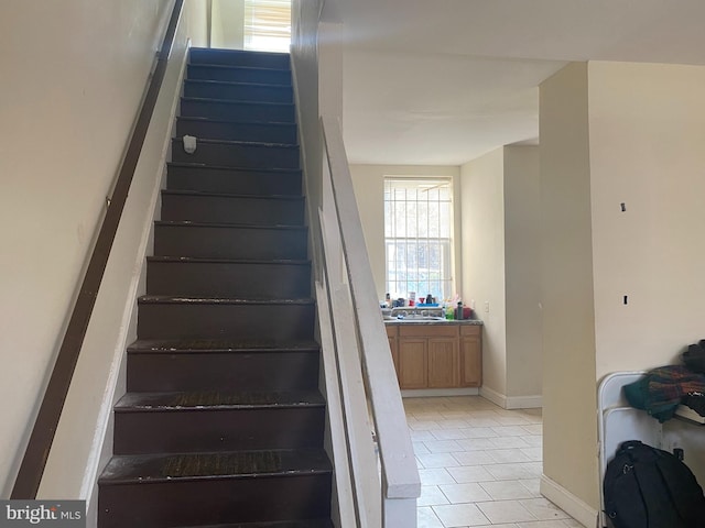 staircase featuring tile patterned floors and sink