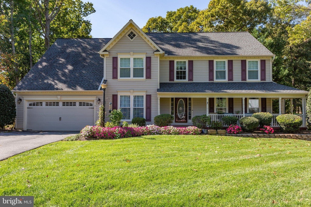 view of front of property with a garage, a porch, and a front lawn