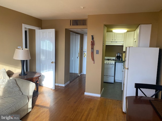 kitchen with white appliances, white cabinetry, and light hardwood / wood-style floors