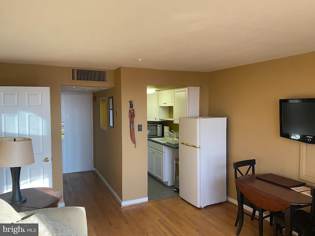 kitchen featuring white cabinets, white fridge, and light hardwood / wood-style floors