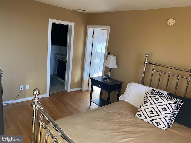 bedroom featuring ensuite bath and hardwood / wood-style floors