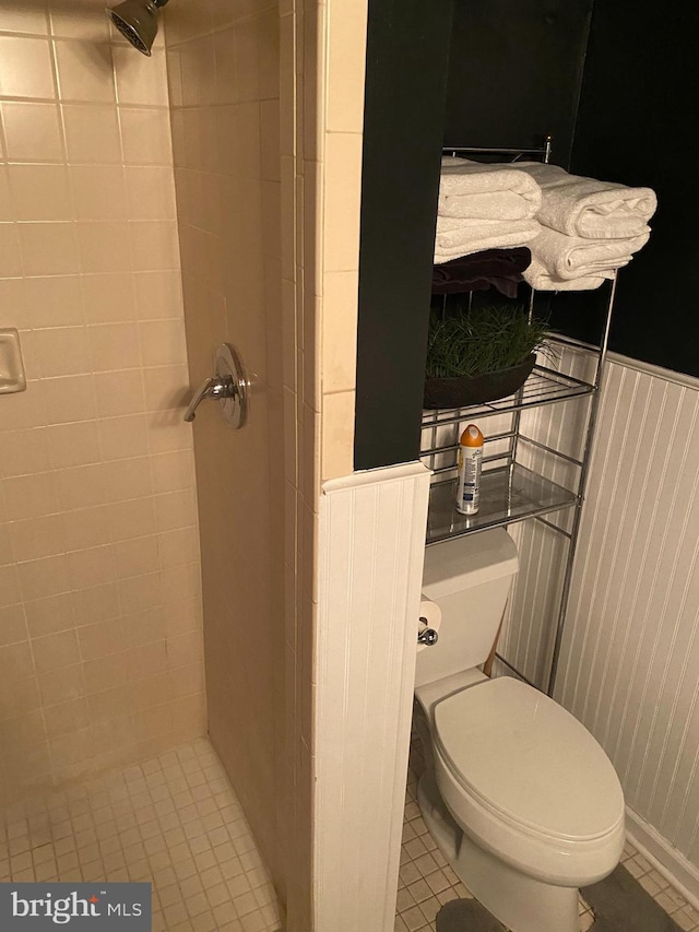 bathroom featuring toilet, tile patterned flooring, and tiled shower