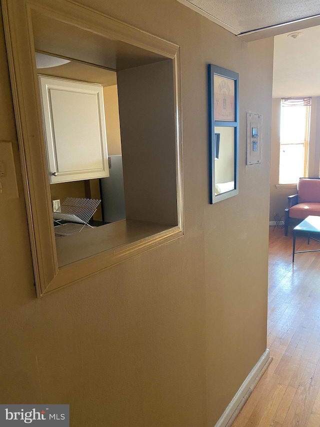 corridor with a textured ceiling and light hardwood / wood-style floors