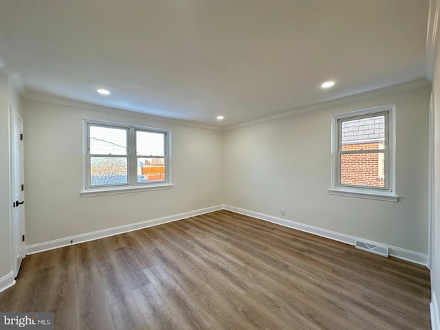 empty room with dark wood-type flooring, ornamental molding, and a healthy amount of sunlight