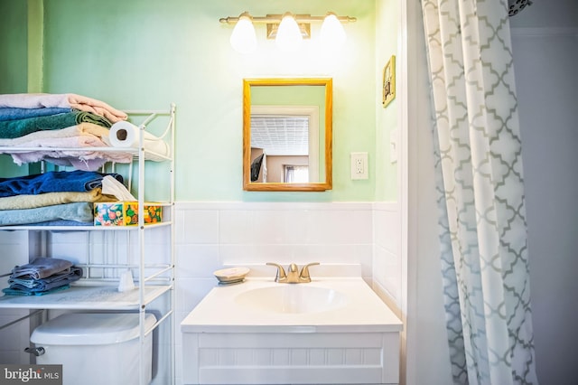 bathroom with toilet, curtained shower, tile walls, and vanity