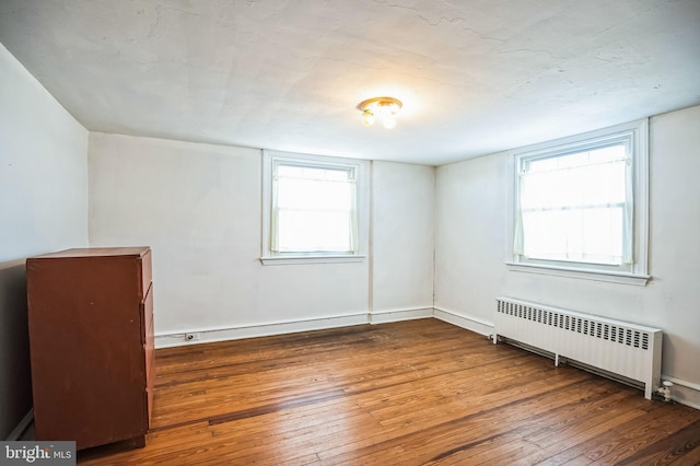 unfurnished room with a baseboard radiator, radiator, and dark hardwood / wood-style floors