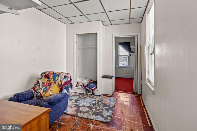 interior space featuring a drop ceiling, a closet, and wooden walls