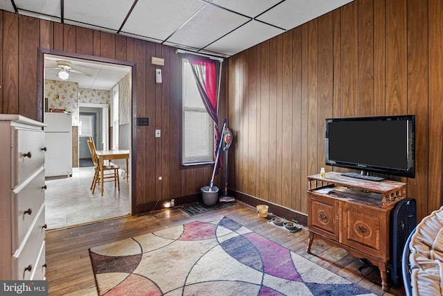 interior space with a drop ceiling, ceiling fan, and dark hardwood / wood-style floors