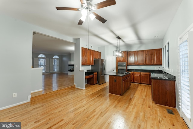 kitchen featuring sink, decorative light fixtures, a center island, light wood-type flooring, and stainless steel appliances