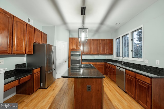 kitchen with sink, hanging light fixtures, a kitchen island, stainless steel appliances, and light hardwood / wood-style floors