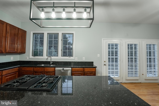 kitchen featuring sink, light hardwood / wood-style floors, black gas stovetop, stainless steel dishwasher, and dark stone counters