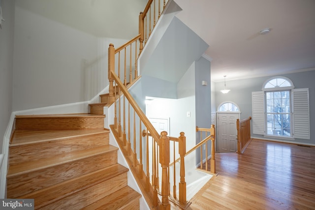 stairs featuring hardwood / wood-style flooring and crown molding