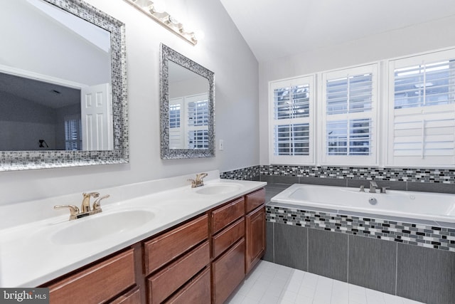 bathroom featuring tile patterned floors, vanity, tiled bath, and vaulted ceiling