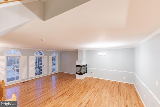 unfurnished living room with ornamental molding, a multi sided fireplace, a notable chandelier, and light hardwood / wood-style flooring