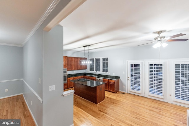 kitchen with sink, hanging light fixtures, a center island, ceiling fan, and crown molding